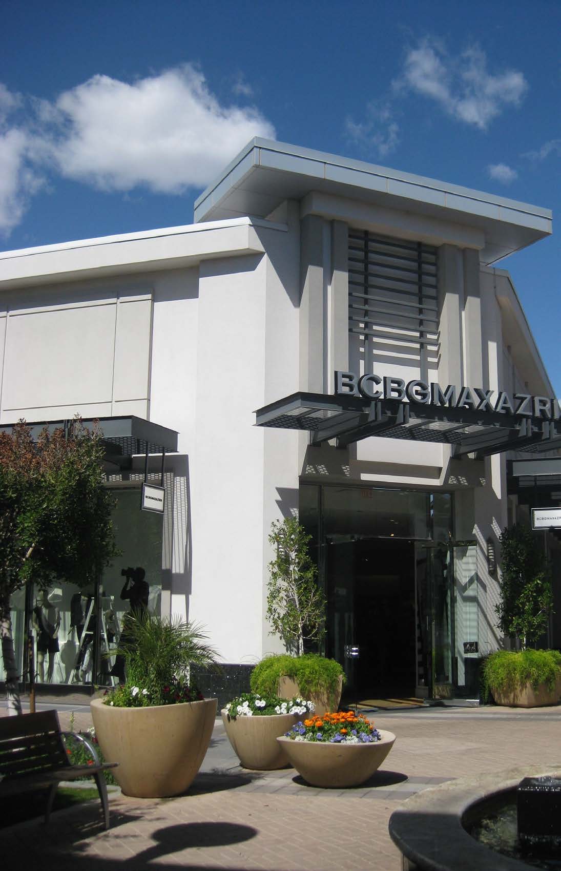 Remodeled storefront at Biltmore Fashion Park with a white canopy blade, dark metal screen, planted containers, and shaded pedestrian walk
