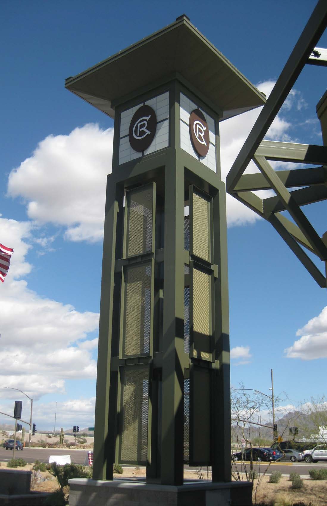 Redesigned signage tower at Chauncey Ranch with a green steel frame, glazed shaft, and circular tenant sign panels