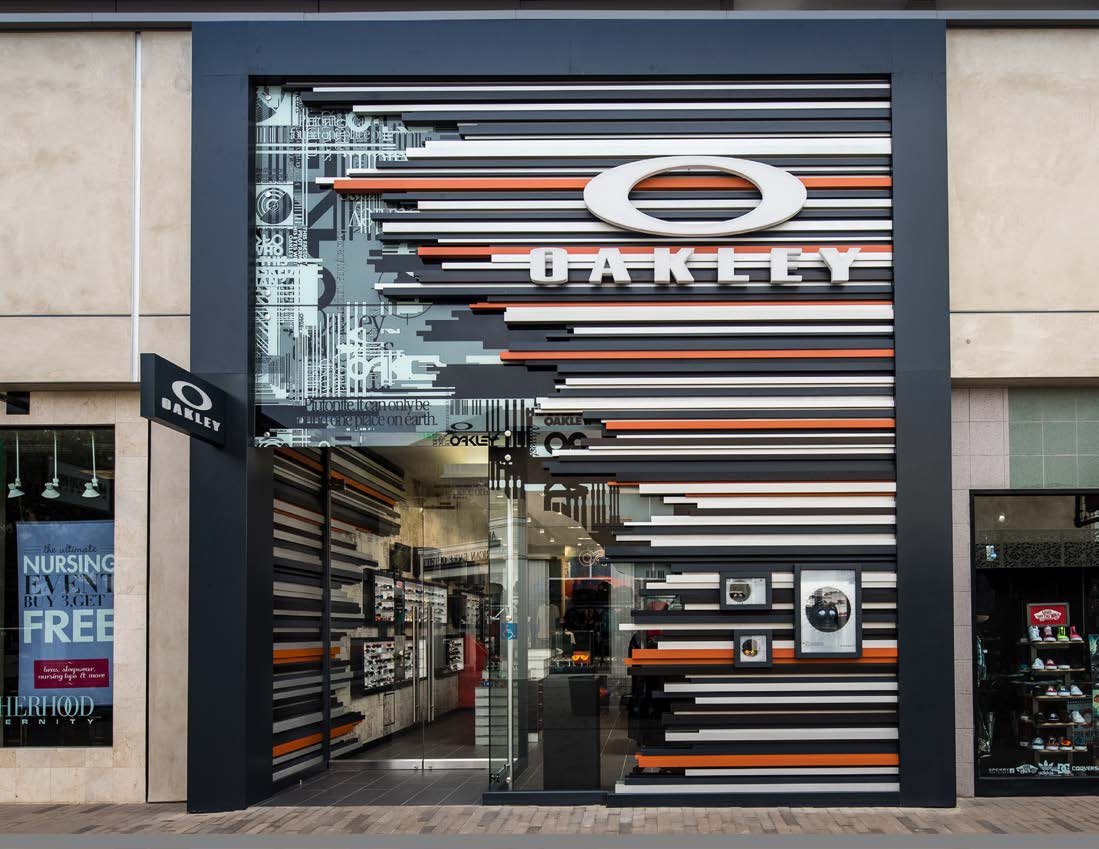 Tenant storefront at University Town Center with a graphic-wrapped facade, dark frame, and illuminated display within the criteria-controlled retail zone